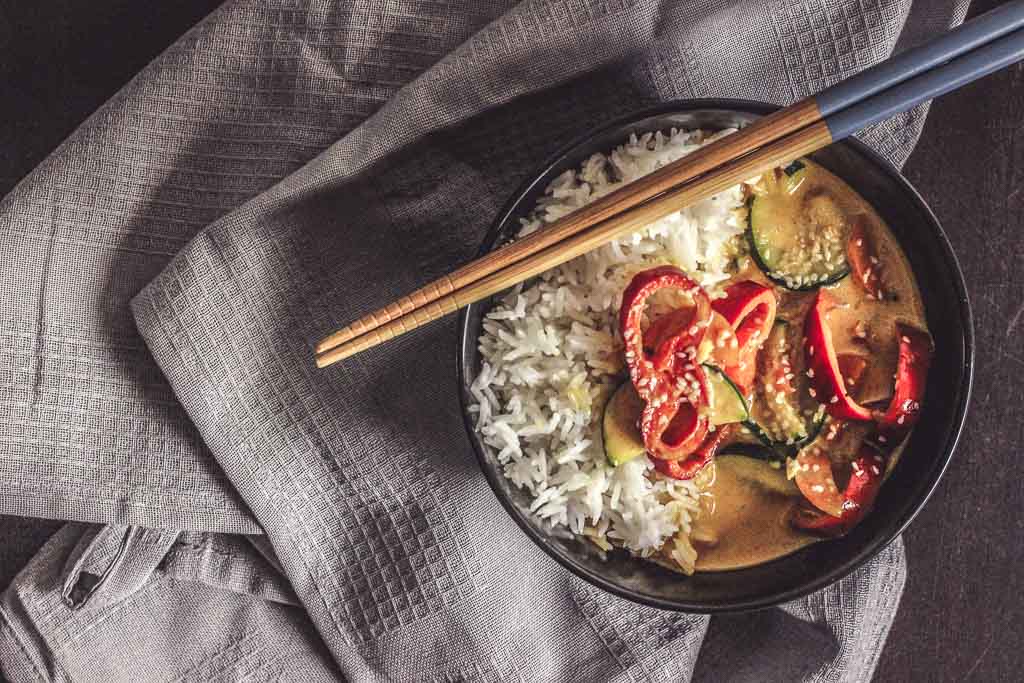 Kokos Thai Curry aus dem Wok mi Chinesischen Stäbchen auf einem Handtuch